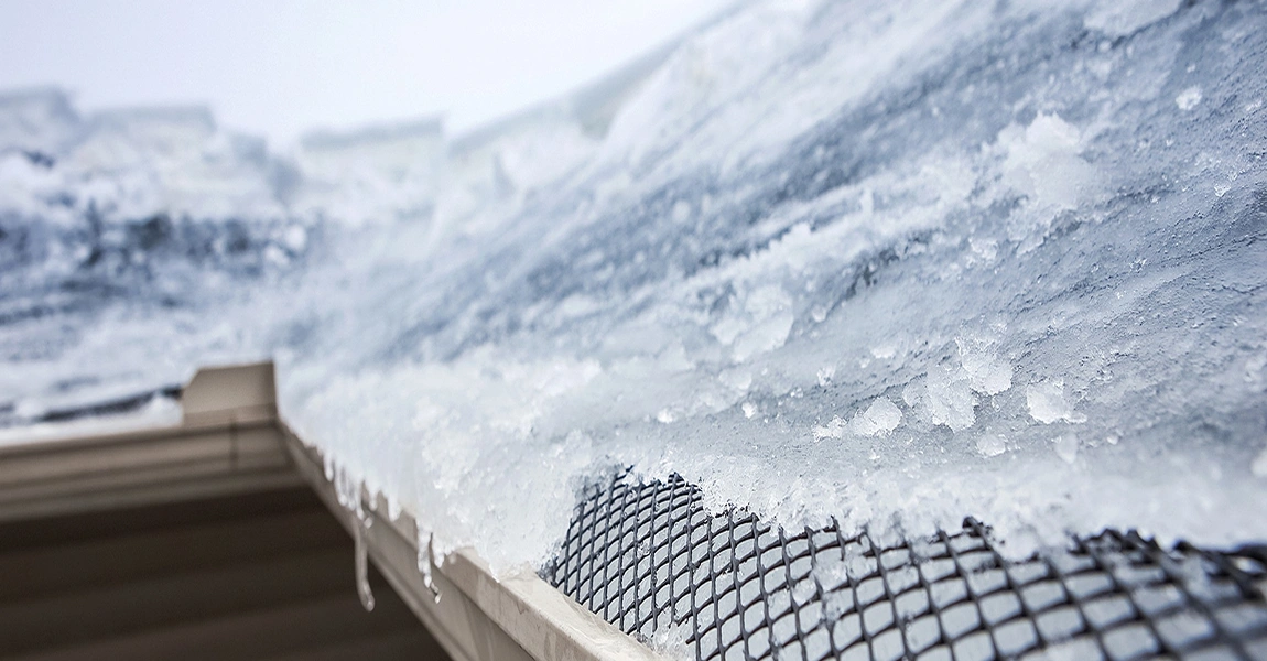 Snow and ice over a mesh-covered roof-edge gutter