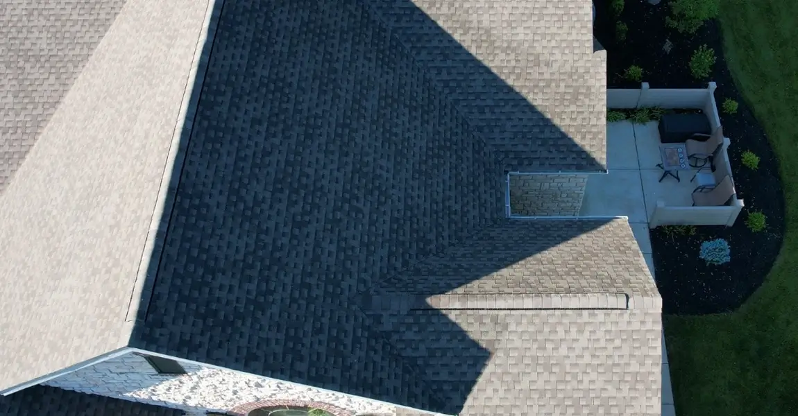 Overhead view of a residential shingle roof beside a patio and yard